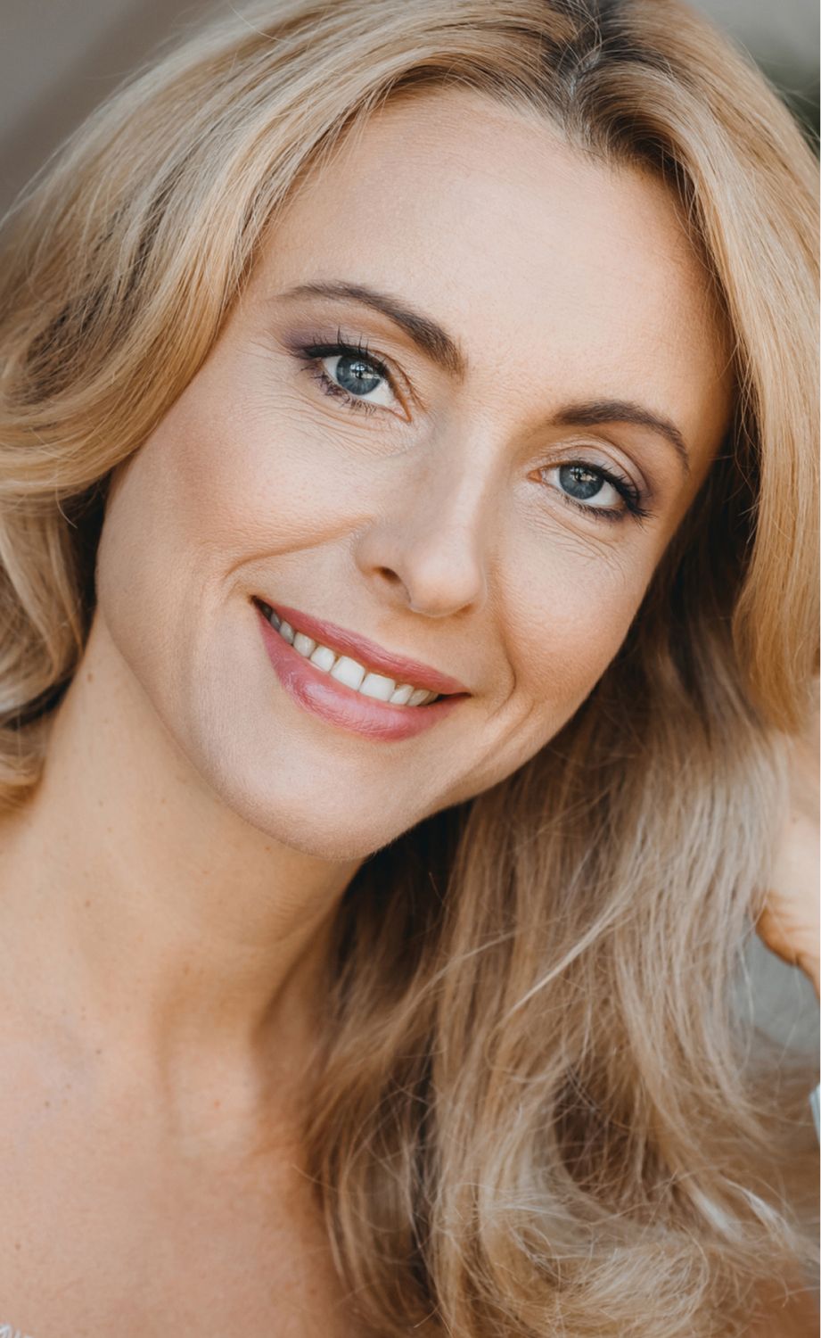 Smiling woman with long, wavy blonde hair.