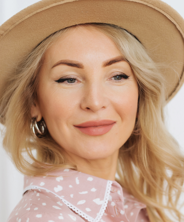 Woman with long hair, natural makeup, thoughtful expression.