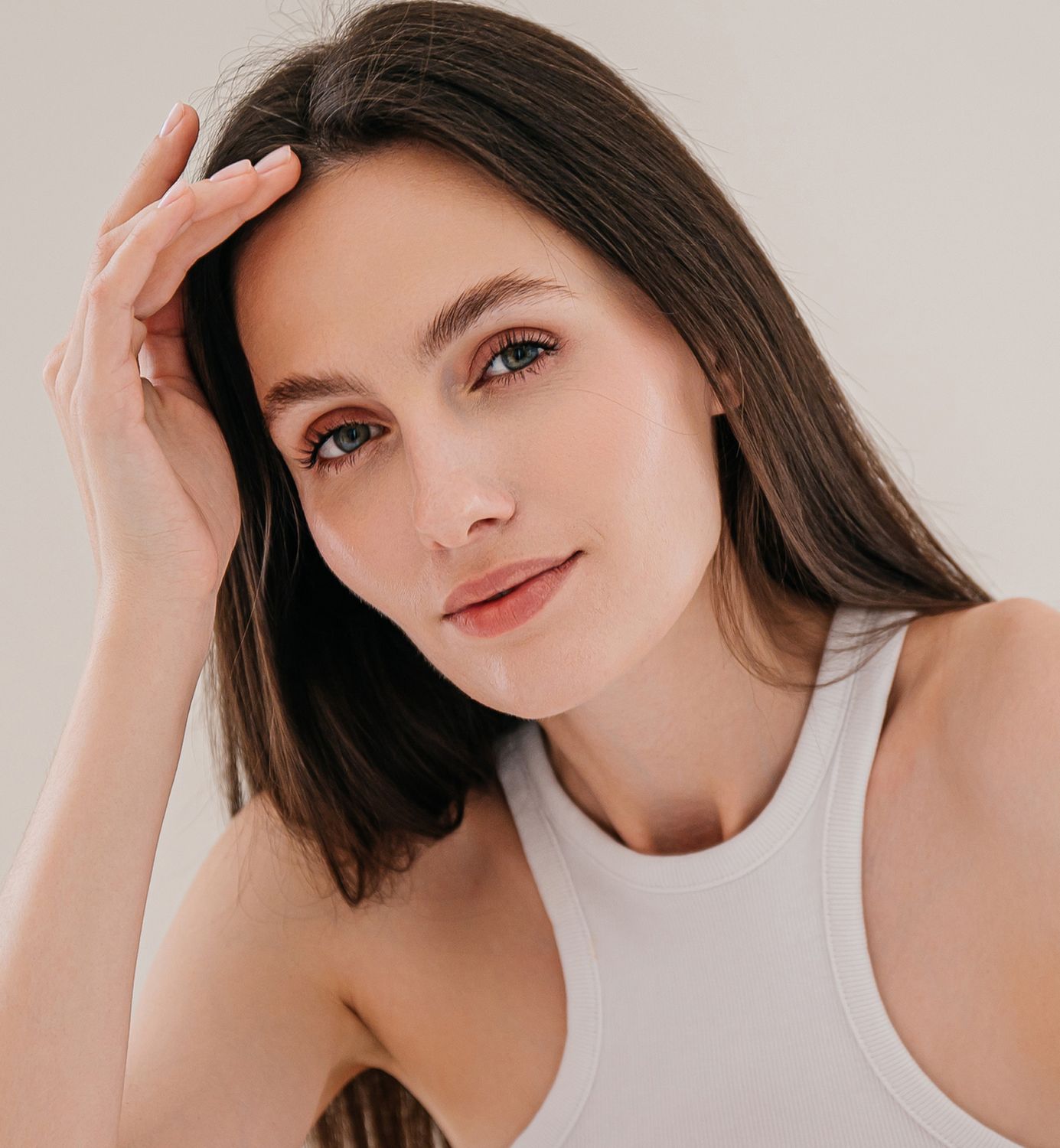 Woman with long hair, natural makeup, thoughtful expression.