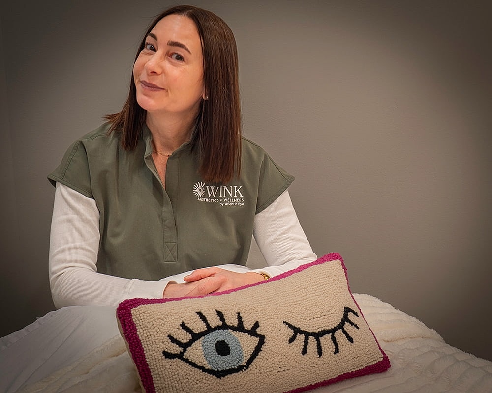 Woman smiling with eye-themed decorative pillow.