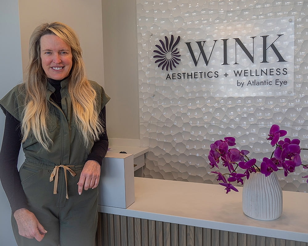 Woman smiling at wellness center reception desk.