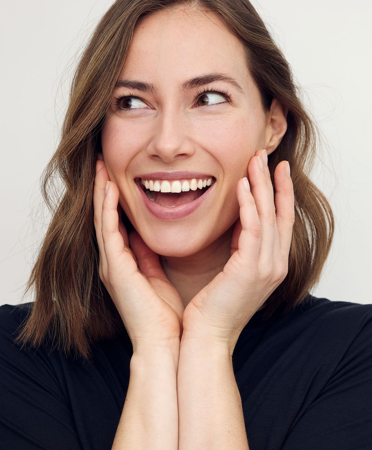 Smiling woman with hands on her cheeks.