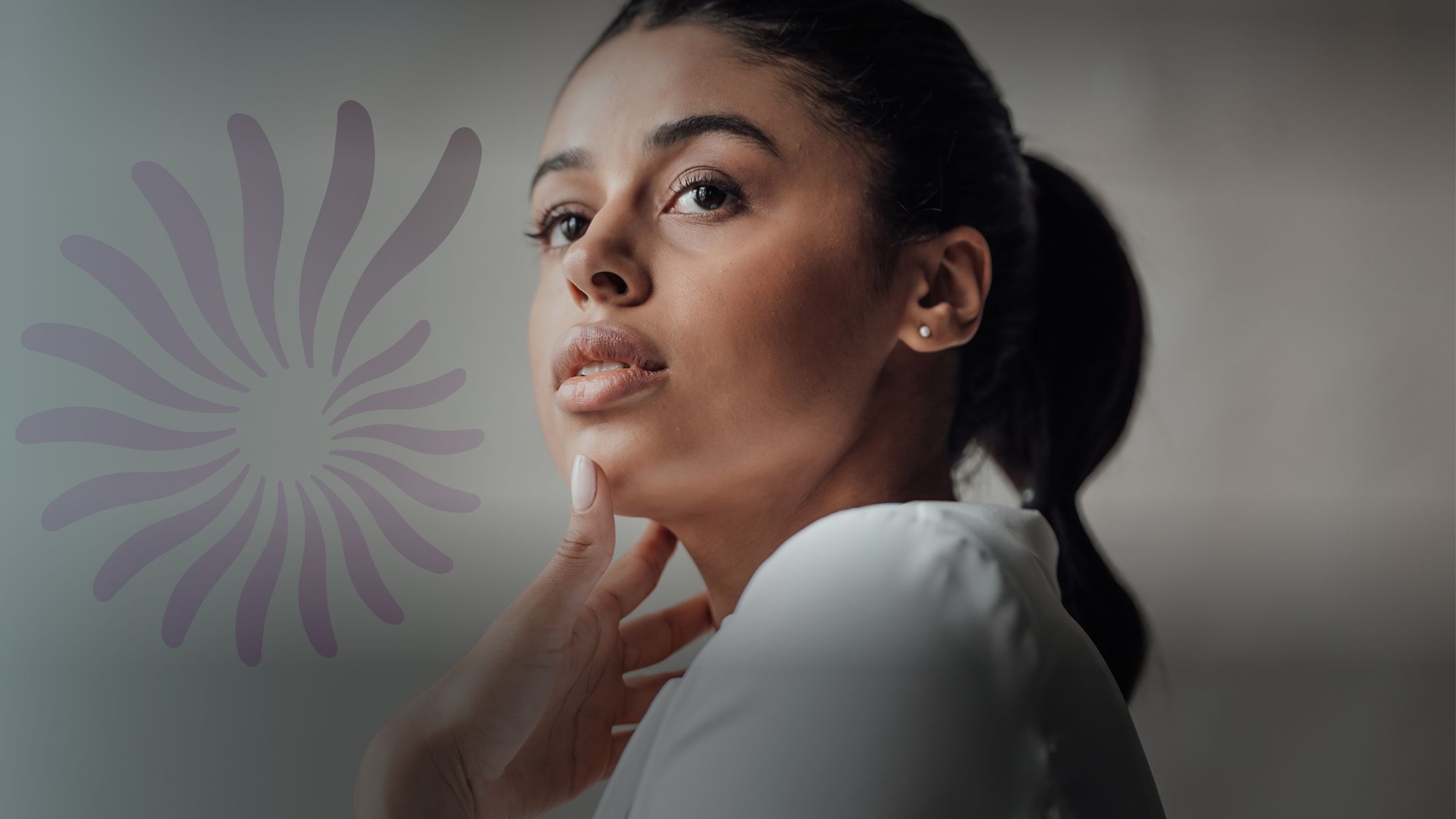 Woman thoughtfully touching her chin, neutral background.