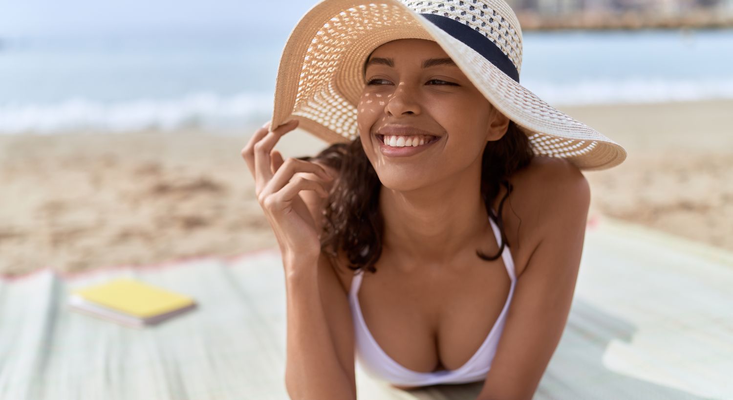Smiling woman relaxing at the beach in sunlight.